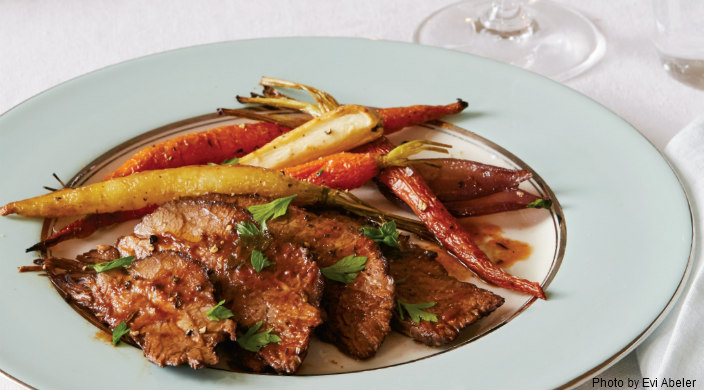 Juicy sliced brisket with colorful roasted carrots and other veggies